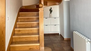 Un escalier en bois à la forme incurvée, menant à un meuble de rangement blanc et à un radiateur.