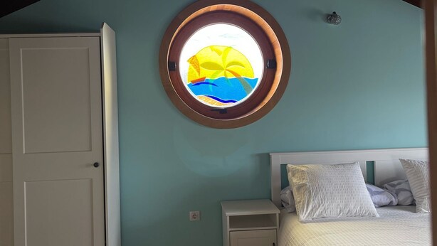 Une chambre avec un puits de lumière, un lit, une table de chevet et une armoire.
