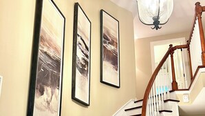 Eine Treppe mit Holzstufen und weißen Geländern, die zu einer Empore mit einer Chandelier führt.