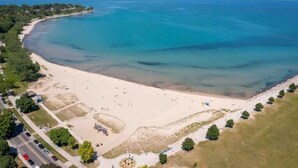 Eine Luftaufnahme eines Strandes mit klarem, blauem Wasser, Sandküste und einigen Personen.