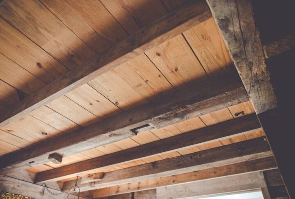 Techo de madera con vigas a la vista y un interior rústico.