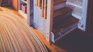 A wooden staircase with a handrail, leading to a landing with a patterned rug. - Audrey's Abode - Restored log cabin, country setting, minutes from Jacksonville
 (Jacksonville)