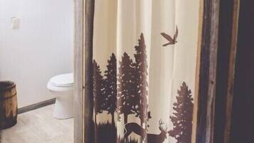 A bathroom with a shower curtain featuring a forest scene.