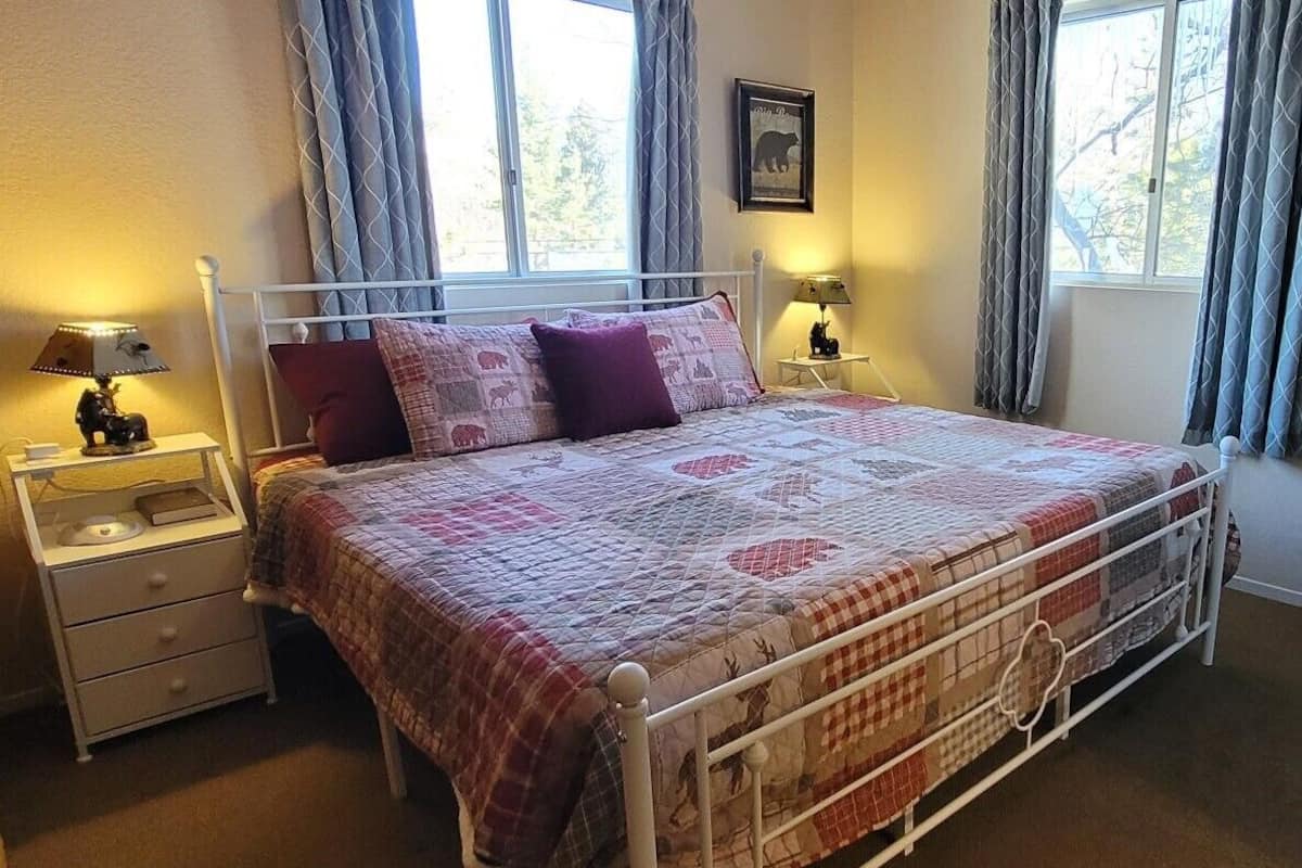 A bedroom with a bed, two bedside tables, a window, and curtains.