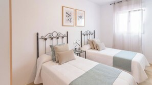 Two single beds with metal frames, a bedside table with a lamp, and a window with curtains. - Villa Paraiso Torrox by Ruralidays (Málaga)