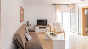 Un salon moderne avec un canapé, un téléviseur, une table basse et un fauteuil.