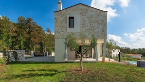 Un bâtiment en pierre avec une petite fenêtre et un arbre devant.