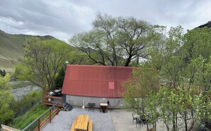 A rustic cabin with a red roof, surrounded by trees and a river.