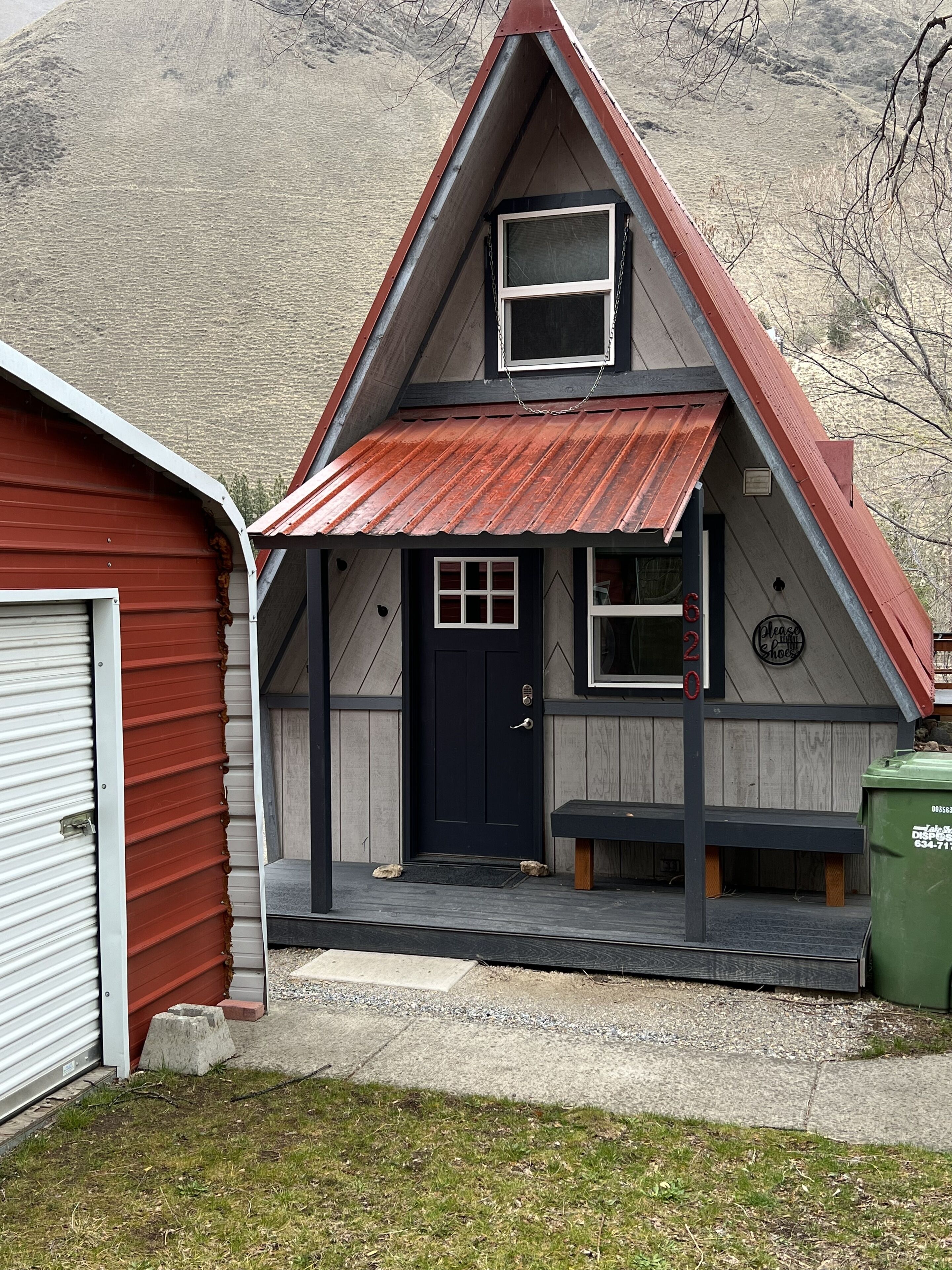 A small, single-story building with a red roof and a black door.