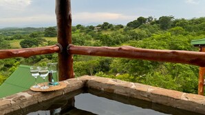 Una fuente de piedra con barandilla de madera y vistas a un paisaje exuberante.