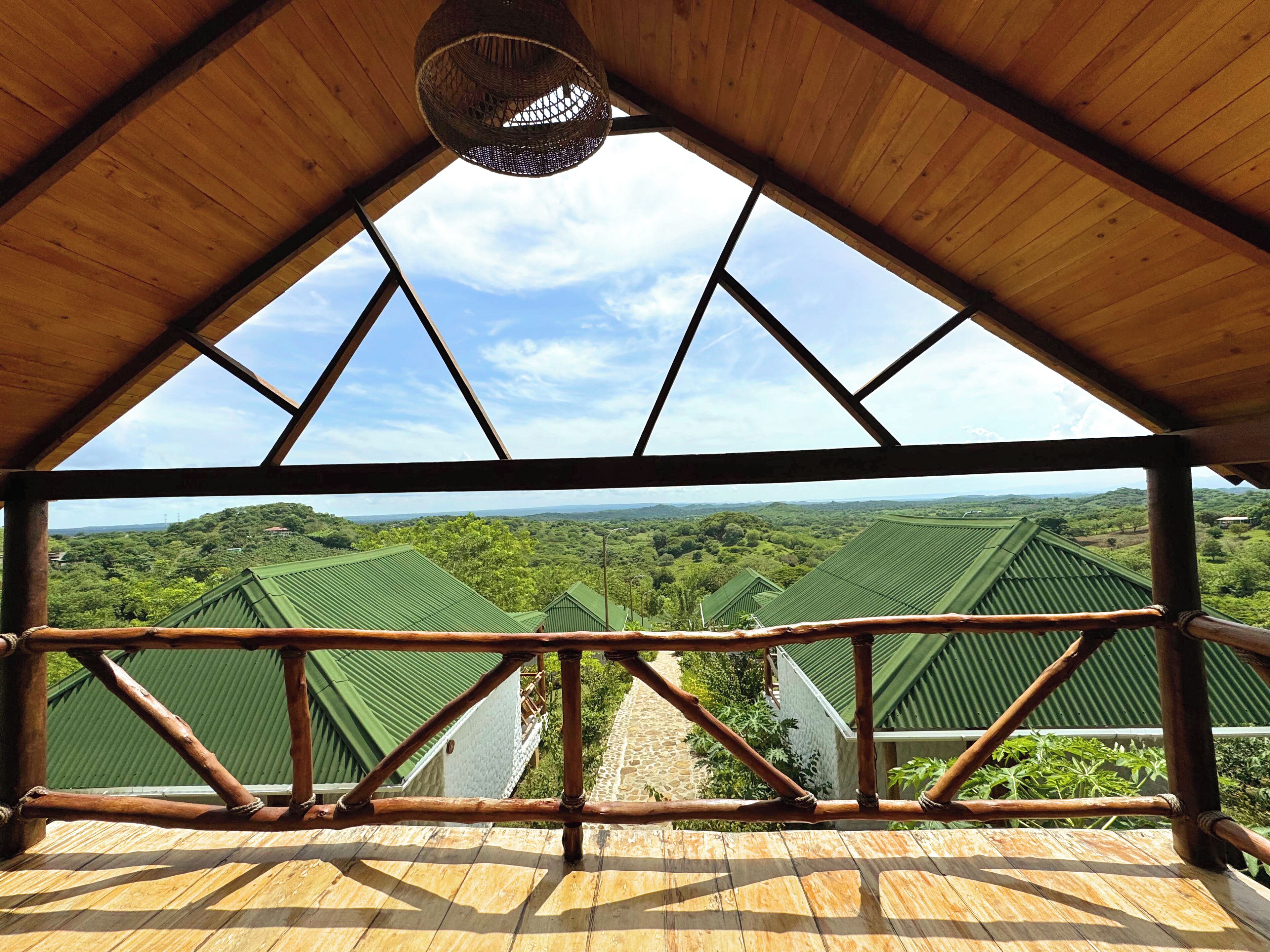 Um deck de madeira com vista para edifícios de telhado verde e uma paisagem arborizada.