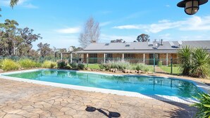 A swimming pool with a stone deck, surrounded by a fence and various plants. - MarMel - Four bedroom home with pool and fire pit (Kangaroo Valley)