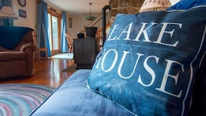 A cozy living room with a blue couch, a stone wall, and a lamp. - Newfound Lake Hideaway Mooring included (Bristol)