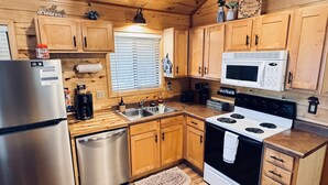 A compact kitchen with wooden cabinets, a stainless steel refrigerator, a microwave, and a stove. - Pet Friendly Retreat in Rim Country! With a Spa! (Overgaard)