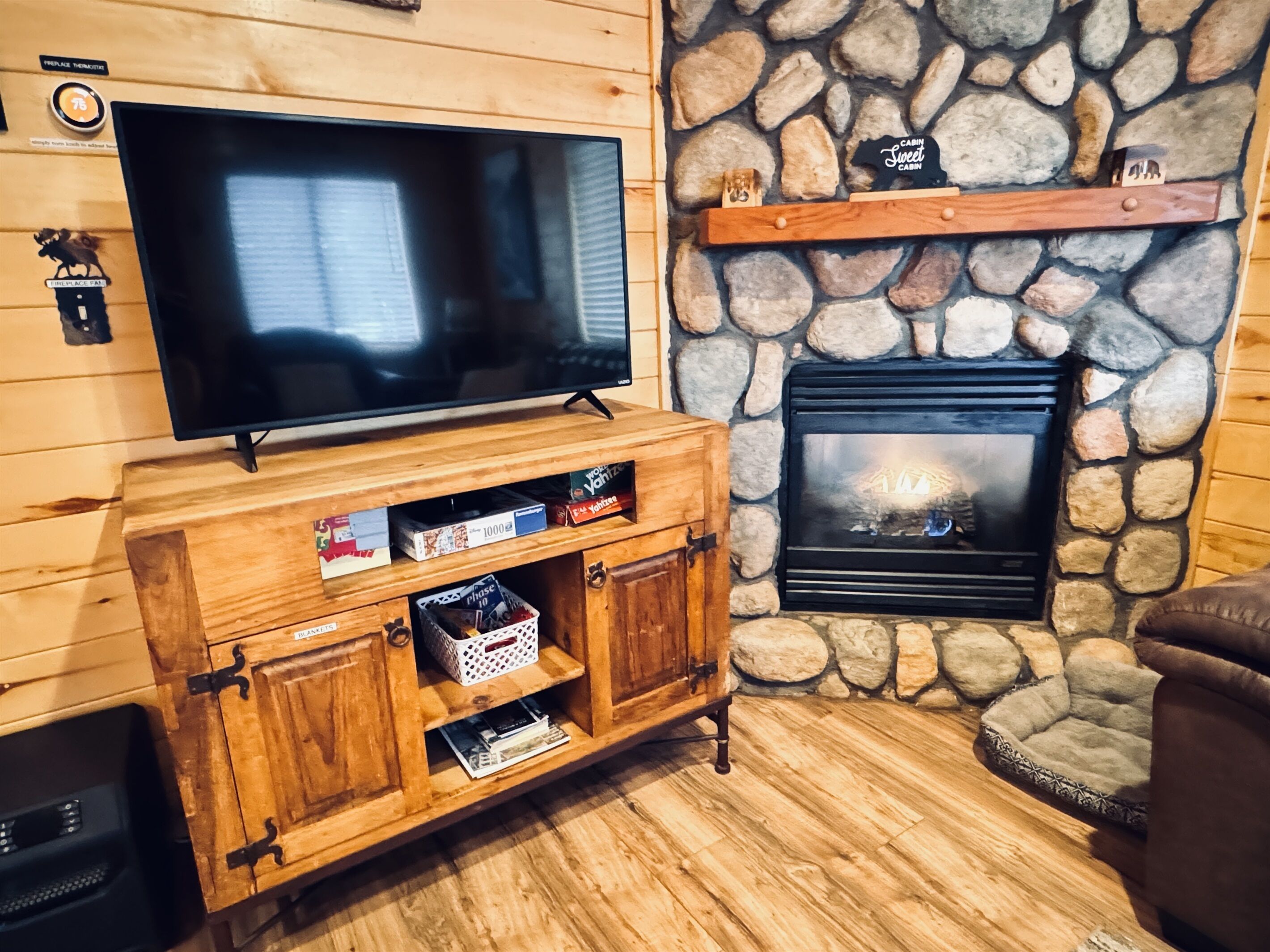 Een gezellige woonkamer met een stenen openhaard, een houten tv-meubel en een televisie.