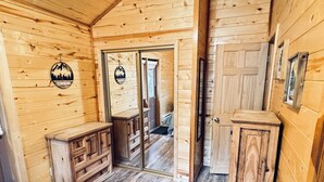A wooden cabin interior with a wooden dresser, a mirror, and a door leading to another room. - Pet Friendly Retreat in Rim Country! With a Spa! (Overgaard)