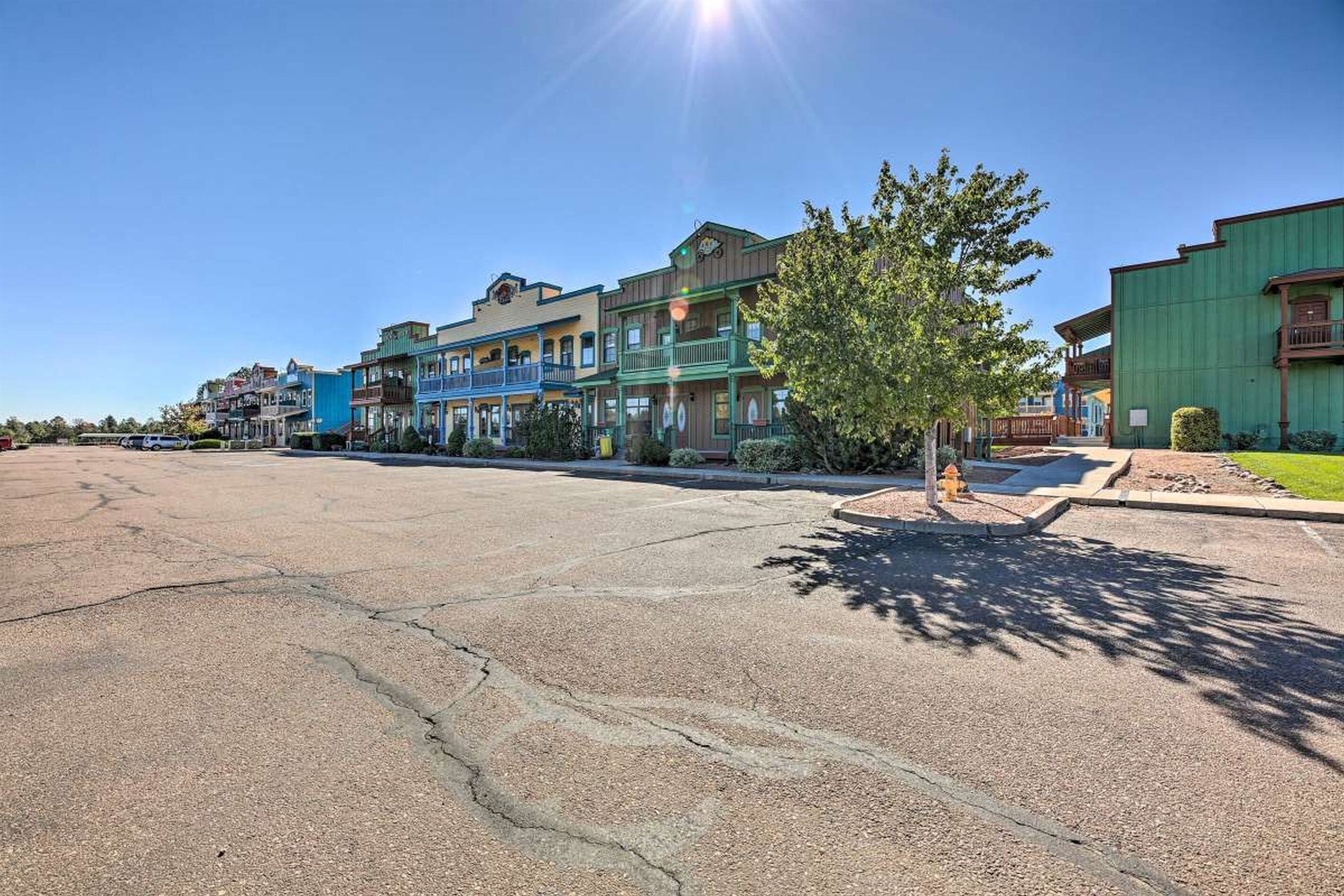 A street with multi-story buildings, a clear sky, and a parking lot.
