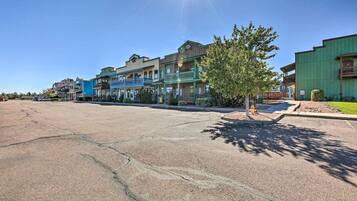 A street with multi-story buildings, a clear sky, and a parking lot.