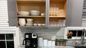 A kitchen with grey cabinets, a coffee maker, and a dishwasher.