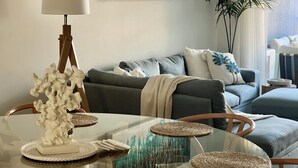 Un salon moderne avec une table basse en verre, un canapé et une lampe.