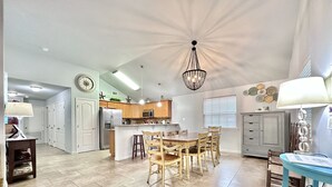 A spacious kitchen with wooden cabinets, a central island, and a dining area with wooden chairs.
