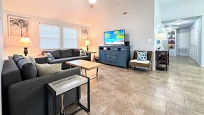 A living room with a sofa, coffee table, TV, and a ceiling fan.