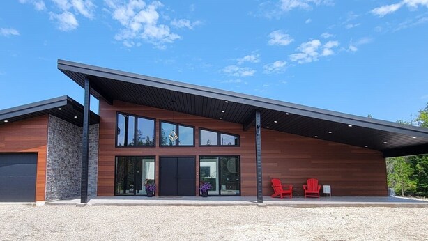 Een modern huis met twee verdiepingen, een garage, grote ramen en een overdekte veranda.