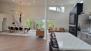 Een moderne keuken met een marmeren eiland, een zithoek met een grote tafel en stoelen, en een woongedeelte met een bank en salontafel.