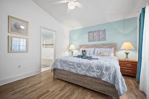 A bedroom with a bed, two bedside tables, a ceiling fan, a bathroom visible through an open door, and artwork on the wall. - Beautiful, sun-drenched 4 Bed 3 Bath Villa within The Sanctuary at West Haven (Davenport)