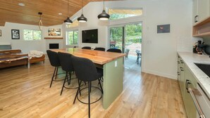 Een moderne keuken met een houten kookeiland, barkrukken en een groot raam.
