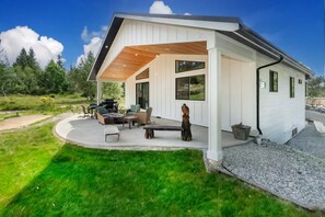 Une maison moderne dotée d’un patio couvert, de mobilier d’extérieur et offrant une vue sur le paysage environnant.