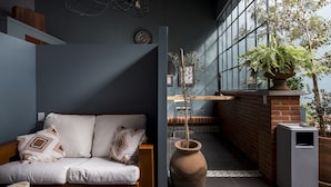 Una sala de estar moderna con un sofá, un ventanal grande y una planta en maceta.