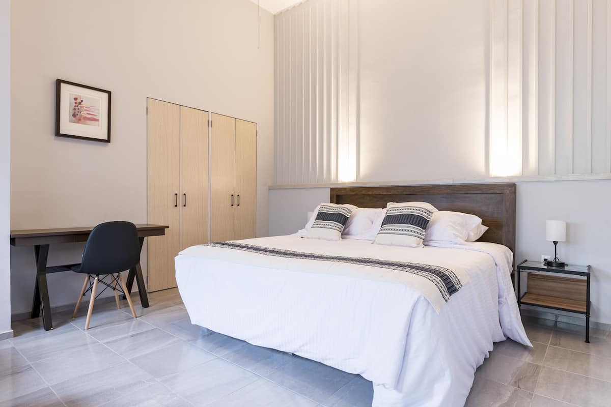 A bedroom with a bed, a desk, and a chair.