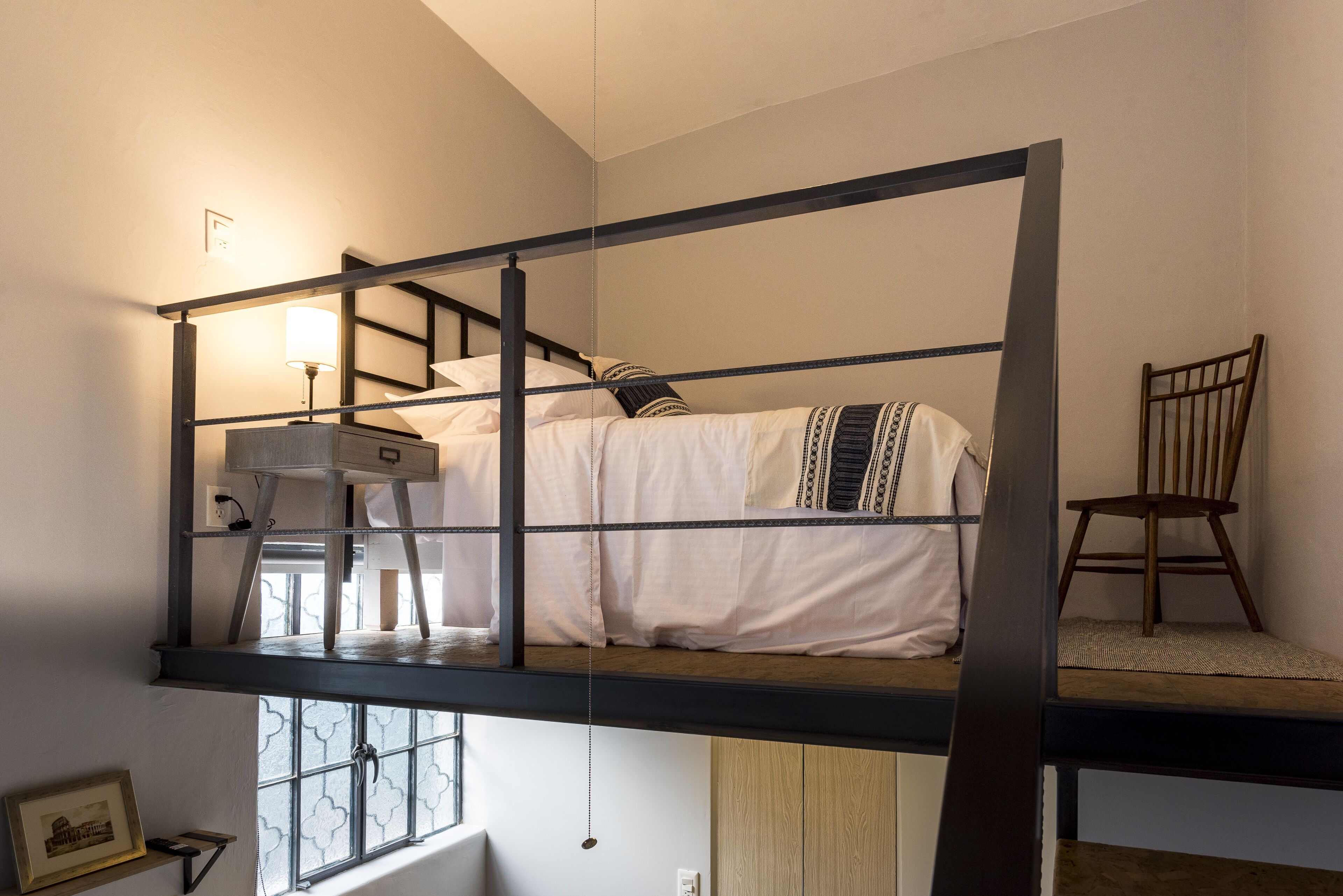 Un letto a castello con una scrivania e una sedia, una lampada a sospensione e una finestra con vista.