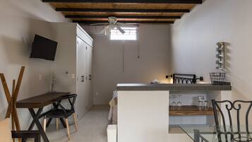 A compact kitchen with a dining area, a ceiling fan, and a window providing natural light.