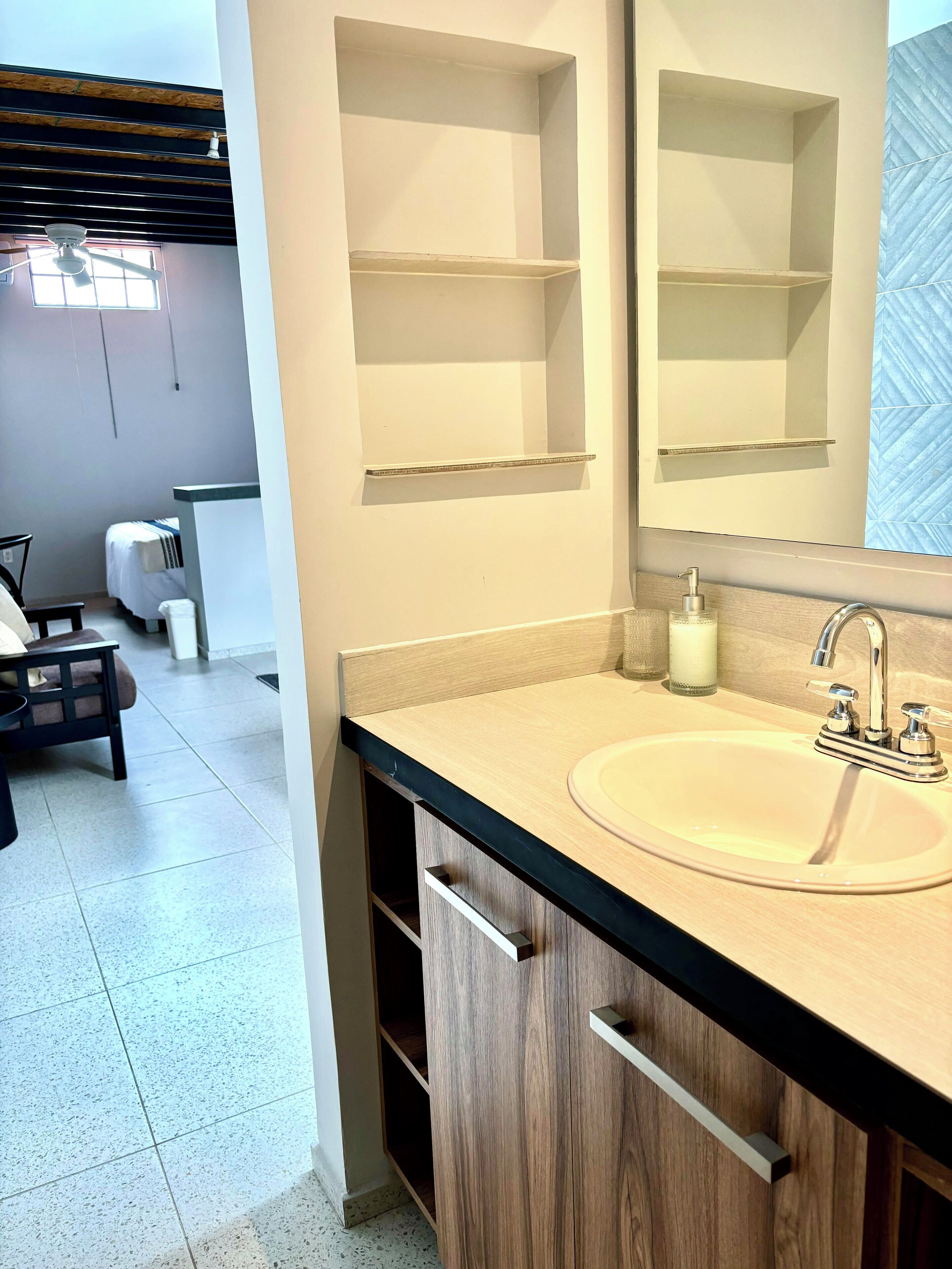 A modern bathroom with a wooden vanity, a large mirror, and a sink.