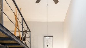 Un interior moderno con una escalera, un sofá, una lámpara y obras de arte enmarcadas en la pared.