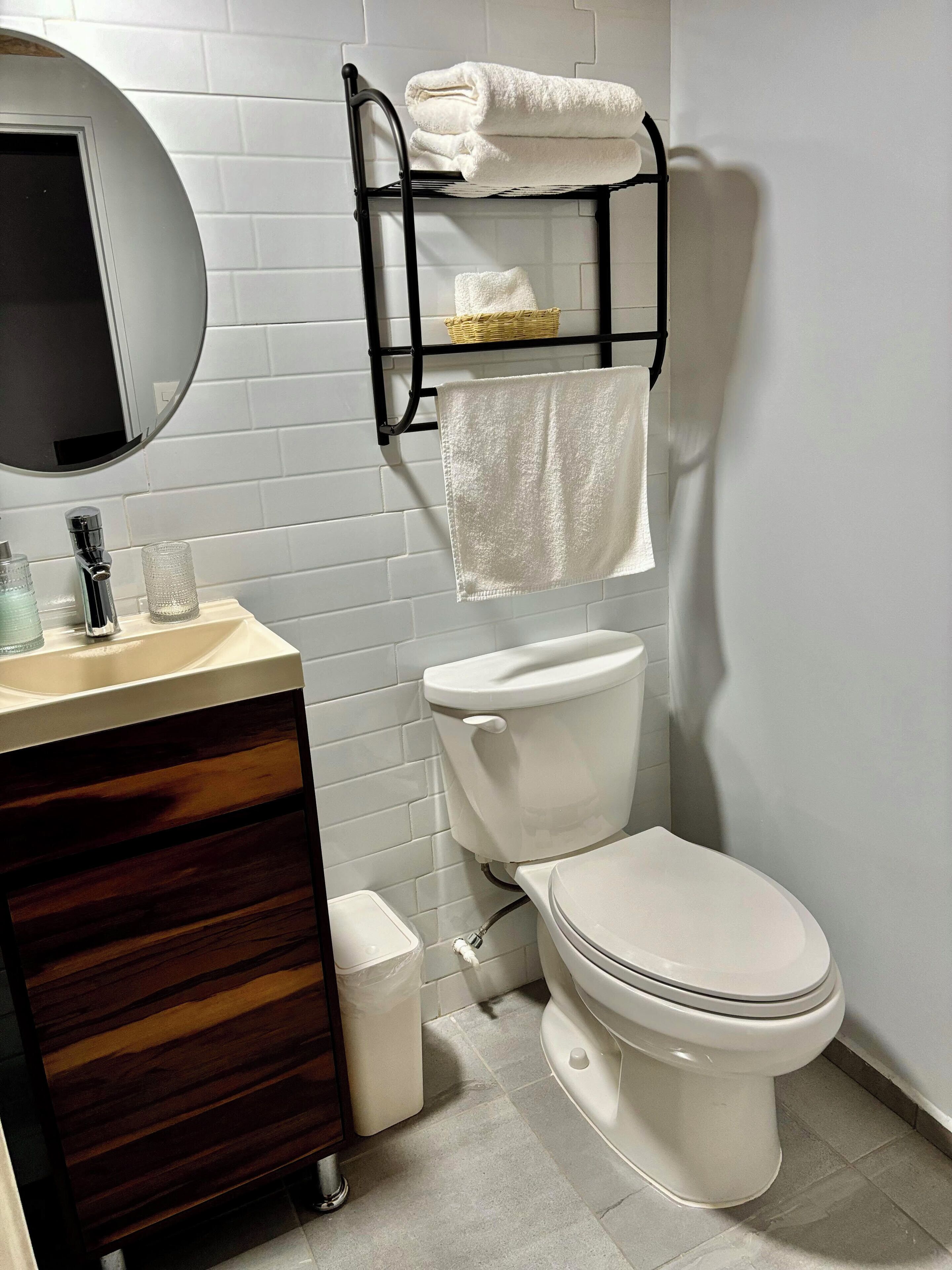 Un baño moderno con inodoro, lavabo con espejo y toallero.