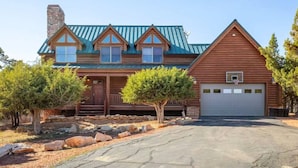 A log cabin with a metal roof, a front porch, and a garage. - Large Log Home Near Zion (Orderville)