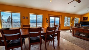 A dining area with a table and chairs, a television, and a balcony with a view. - Breathtaking Views Close to Yellowstone (Island Park)