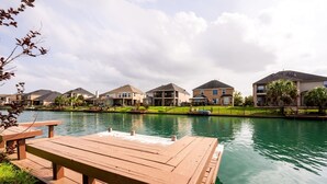 Vista al lago con muelle de madera y mesa de picnic.
