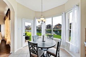 A dining area with a round table, chairs, and a chandelier.