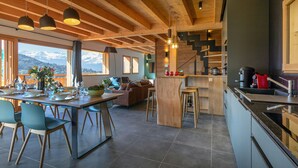 A modern kitchen with a central island, bar stools, and a dining area with a view of mountains.