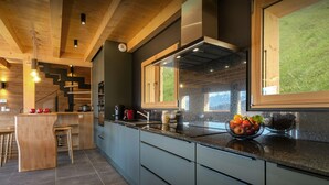 A modern kitchen with a granite countertop, wooden cabinets, and a large window.