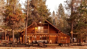 Une cabane en rondins dotée d’un balcon, entourée d’arbres et offrant un espace de détente extérieur.