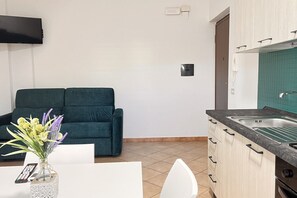 A compact living space with a kitchenette, a sofa, and a dining area.