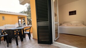 Ein Zimmer mit einem Bett, einem Tisch mit Stühlen und einer Schiebetür zu einem Außenbereich.