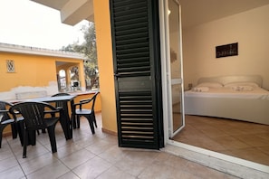 Ein Zimmer mit einem Bett, einem Tisch mit Stühlen und einer Schiebetür zu einem Außenbereich.