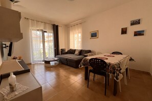 Ein Wohnzimmer mit einer Couch, einem Esstisch, Stühlen und einer Lampe.
