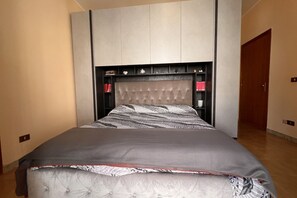 A bedroom with a bed, a headboard with shelves, and a door.